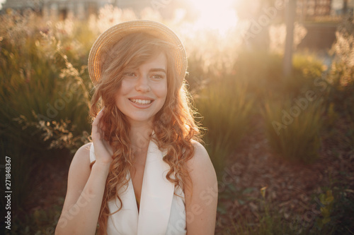 Portrait of young positive woman with curly hair in straw hat
