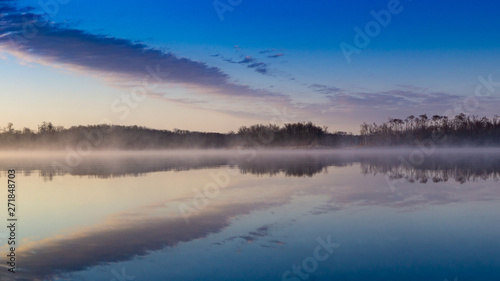 Sunrise lake and sky mirrored images, Calm as glass lake water reflecting the sky above, misty water