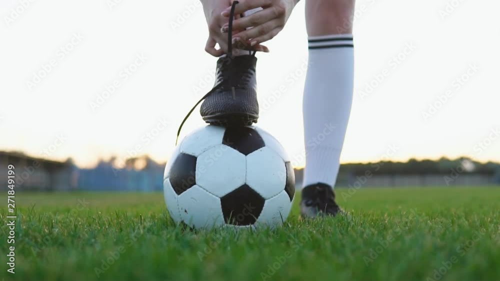 Close up of a female soccer player tying shoelace on football field, slow motion
