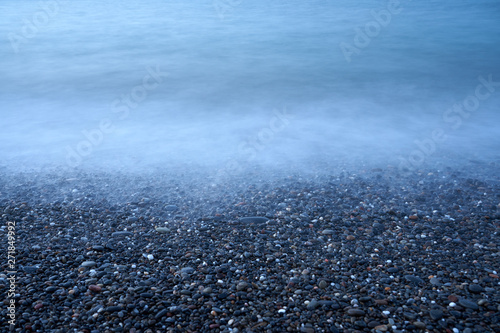 Pebble in water on the beach. Natural background. Copy space.