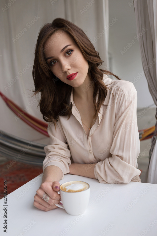 Portrait of young sensual woman drinking coffee on a cafe veranda. Concept of relaxation and city leisure Portrait of young sensual woman drinking coffee on a cafe veranda. Concept of relaxation and city leisure