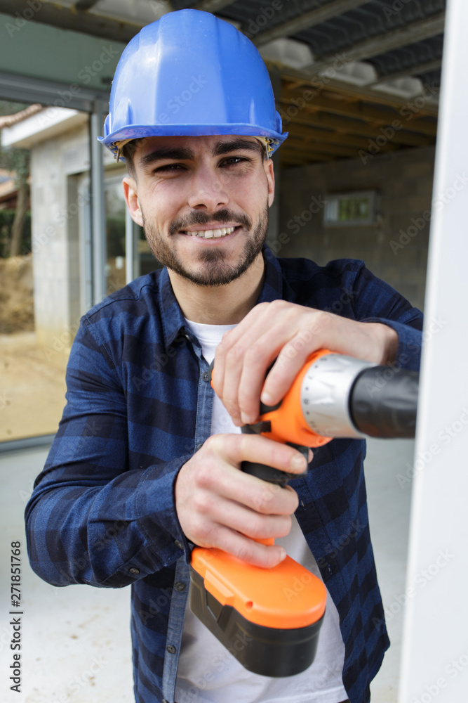 worker smiling and holding a drill outdoors worker smiling and holding a drill outdoors