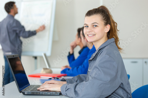 фотографія portrait of female blue-collar aprpentice using laptop in classroom