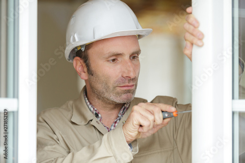 repairman fixing window with screwdriver