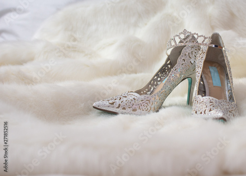 the bride's tiara sits on top of her silver sequined high heel shoes on a clean white fur coat