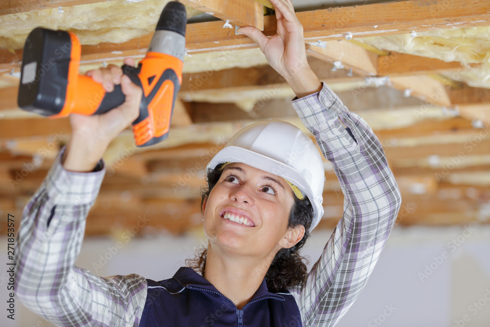 female builder using cordless drill overhead - obrazy, fototapety, plakaty 