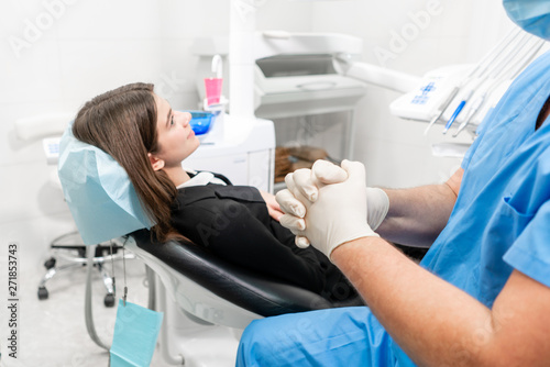 The doctor puts on rubber gloves. Doctor treats teeth. Medicine  health  stomatology concept. dentist treating a patient. . Young beautiful woman in the dentist chair at dental clinic.