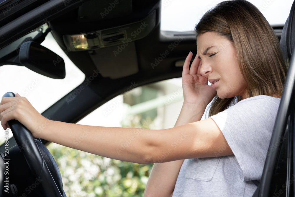 female driver holding her head in pain