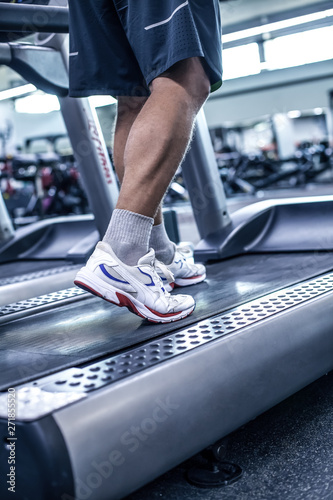 Run to success. Close-up part of man in sports shoes running on treadmill at gym