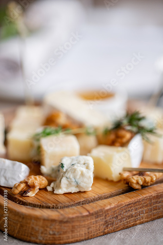 Cheese plate. Delicious cheese mix with walnuts, honey on wooden table. Tasting dish on a wooden plate. Food for wine. Buffet at the gala dinner.