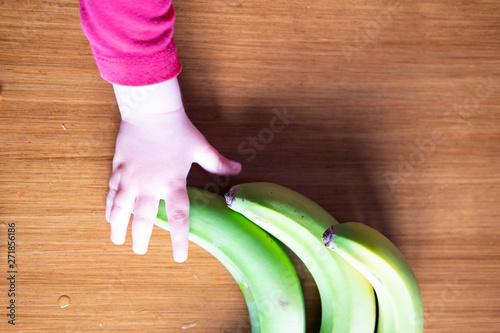 Baby s hand manipulating different fruits on a wooden table photo