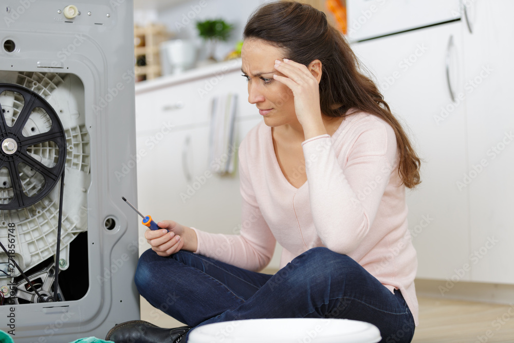 female trying to fix a washing machine female trying to fix a washing machine