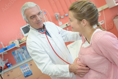 Canvas-taulu doctor using a stethoscope listening to fetus