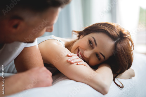 Cute woman smiling to man while lying next to him