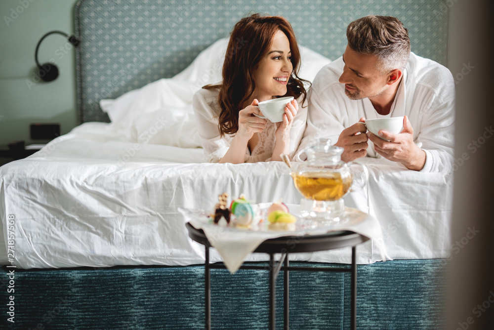 Lovely couple lying on the bed and drinking tea