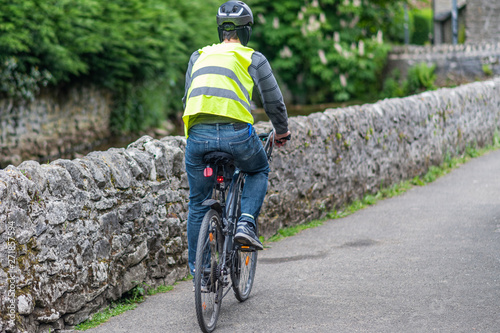 A male cyclist rides a bike in full safety gear - Helmet, high visibility jacket, bike lights