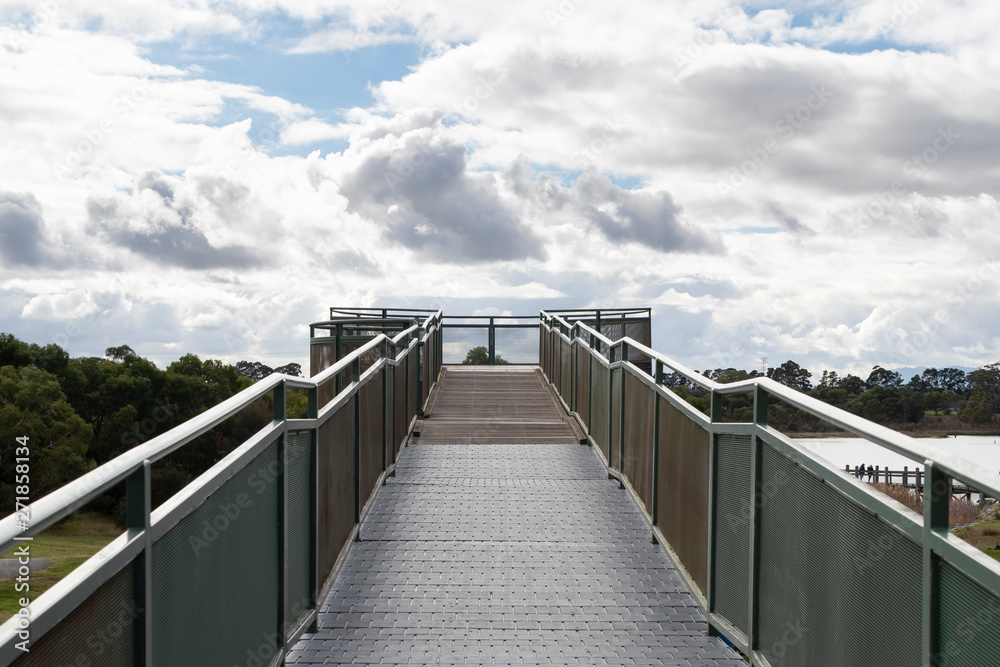 Fototapeta premium A walkway and viewing platform overlooking a lake in a community park.