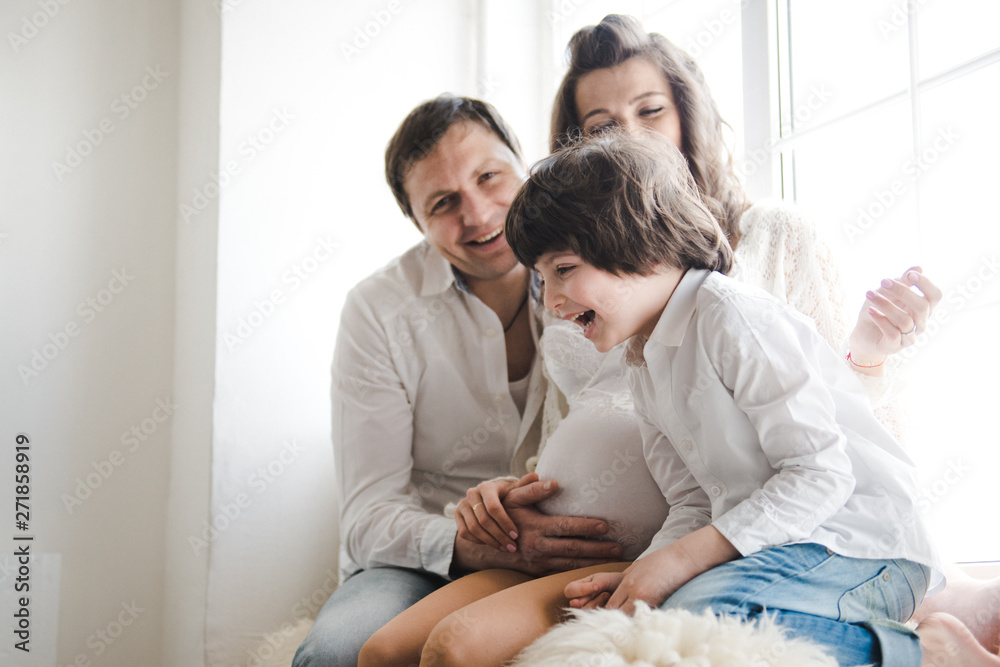 Happy family waiting for a second child. Pregnant woman with husband and little boy . Happy family on white background. Second pregnancy, maternity concept. Happy family waiting for a second child. Pregnant woman with husband and little boy . Happy family on white background. Second pregnancy, maternity concept.