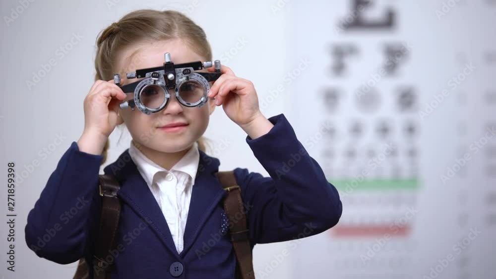 Optometrist putting optical trial frame on schoolgirl to determine visual acuity Optometrist putting optical trial frame on schoolgirl to determine visual acuity