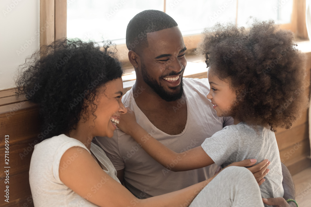 Obraz premium Happy black family bonding laughing sit on bedroom floor