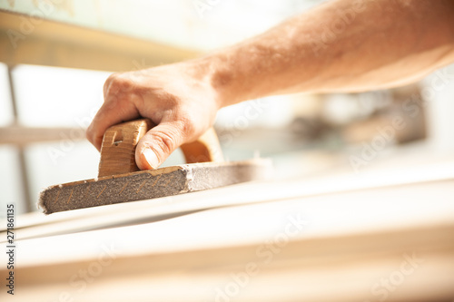 Person sanding wood plank to be completely smooth