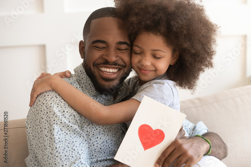 Фотография African dad embracing daughter holding greeting card on fathers day