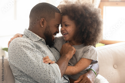 Happy african father and cute child daughter bonding embracing laughing