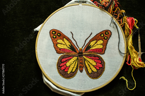 Canvas Print Bright butterfly embroidered on white cotton fabric stretched on a wooden hoop w