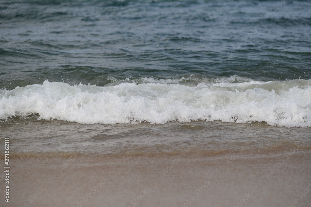 closeup on waves hitting the beach on a sunny summer day