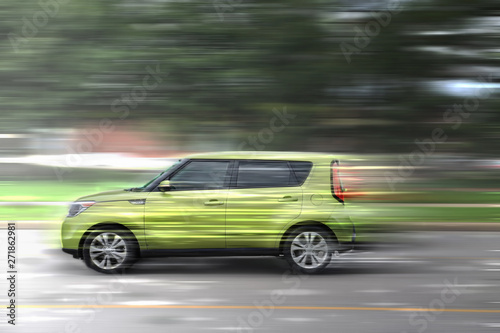 A green car at high speed rides along the road, speed in motion