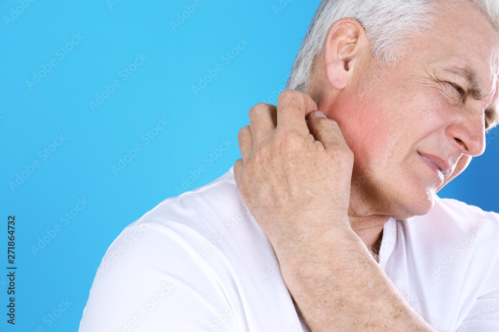 Obraz premium Senior man scratching neck on color background, closeup with space for text. Allergy symptom