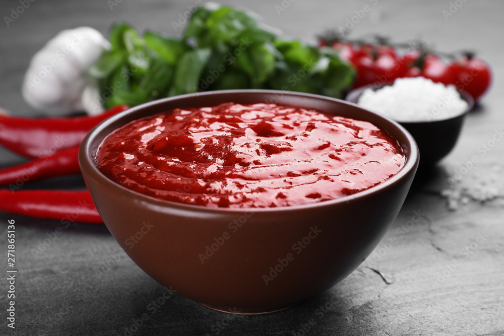 Bowl of spicy chili sauce on grey table, closeup Bowl of spicy chili sauce on grey table, closeup