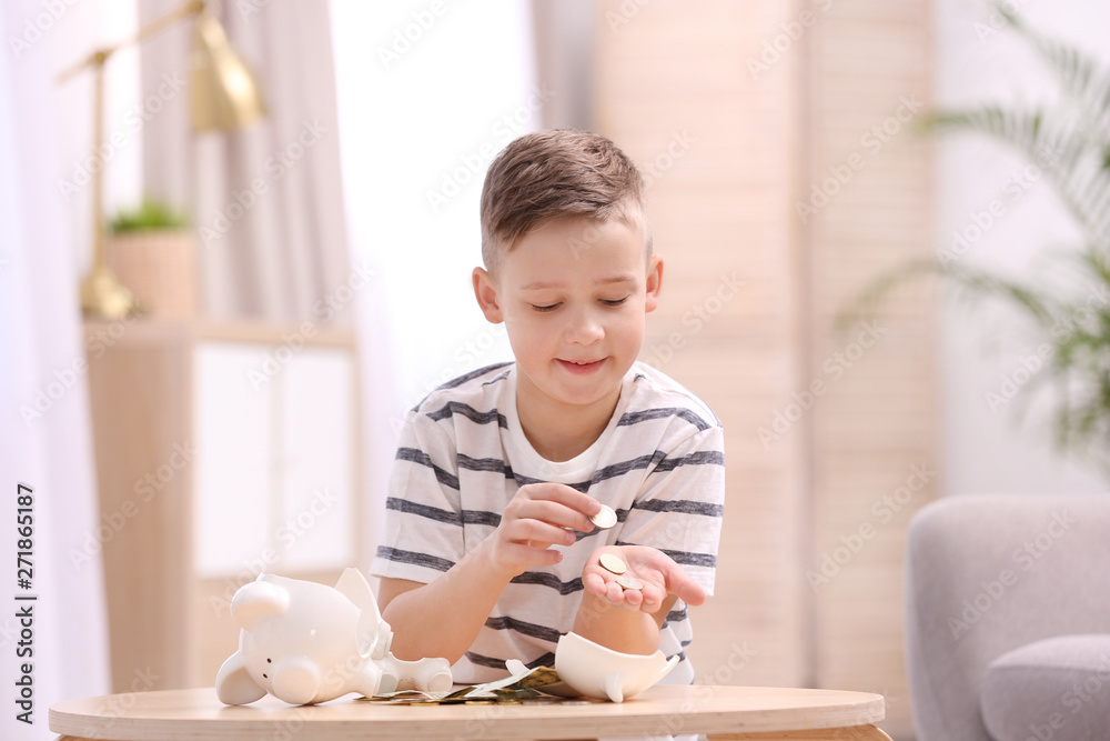 Little boy with broken piggy bank and money at home Little boy with broken piggy bank and money at home