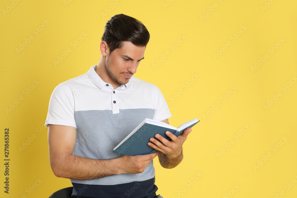 Handsome man reading book on color background, space for text Handsome man reading book on color background, space for text