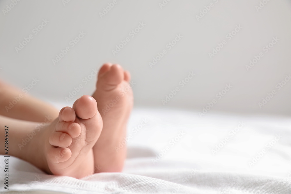 Little baby lying on bed sheet against light background, closeup. Space for text Little baby lying on bed sheet against light background, closeup. Space for text