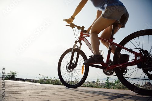 Cycling woman riding mountain bike on sunrise seaside