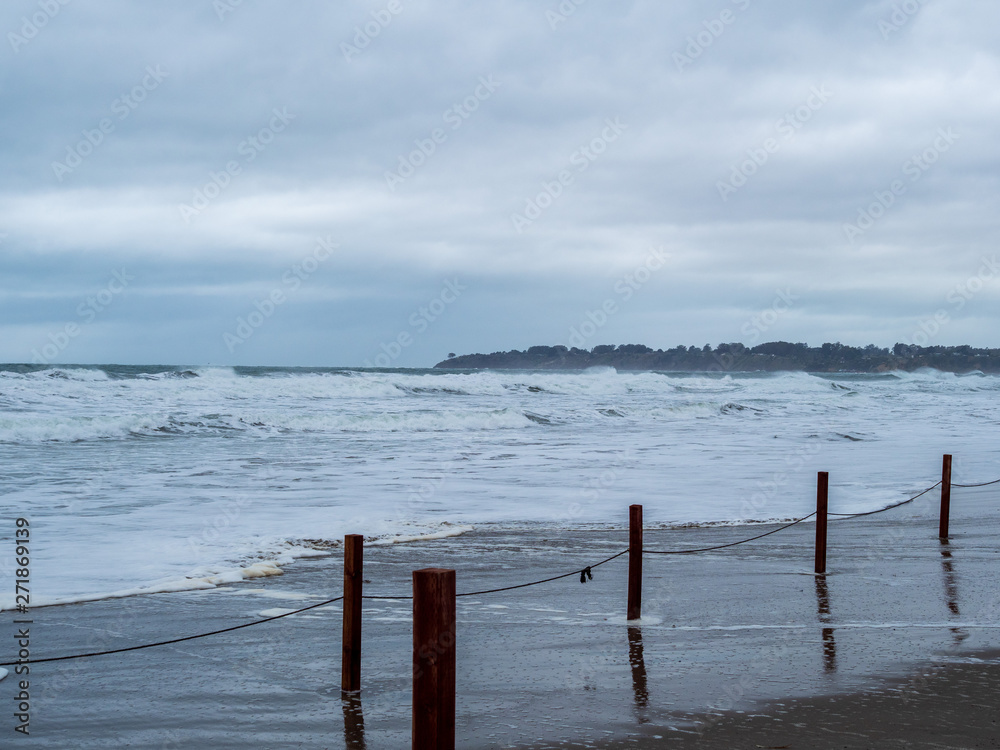 Makeshift fence of wooden posts and strings on a storm beach with waves coming on shore Makeshift fence of wooden posts and strings on a storm beach with waves coming on shore