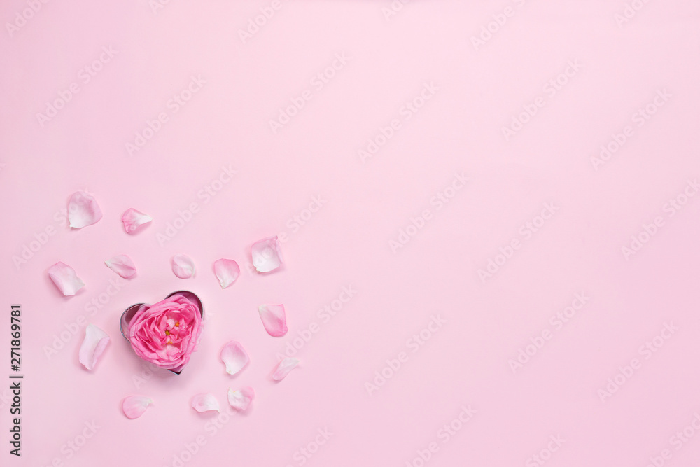 Heart shaped cookie cutter with rose and petals on pink background. Valentine day baking concept.Top view, Copy space