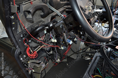 A lot of ravel multicolored wires from the car wiring lies in the cabin of dismantled car with connectors and plugs, a view through the window inside the battered car. Auto service industry © Aleksandr Kondratov