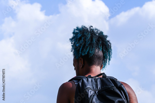 Rear view of young African man with backpack stand and blue sky background. Traveler concept.
