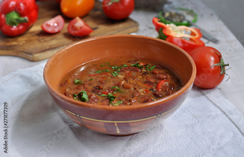 Spicy red beans. Hot homemade bean soup with tomatoes and peppers in a ceramic bowl.