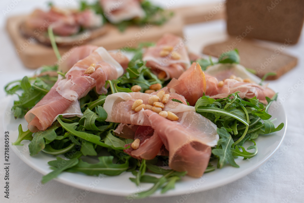 Healthy salad with prosciutto, tomato and green leaves