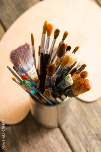 bundle of artist's paintbrush at tin can, blank palette, rusty wooden