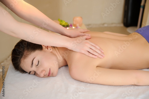 lateral view of a young woman receiving a neck and shoulders massage done by a masseuse in a spa salon