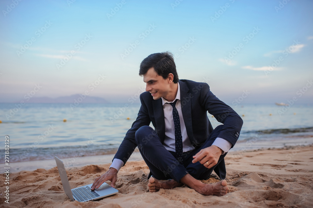 close up photo of a young man in suit with laptop working on the beach and talking to someone close up photo of a young man in suit with laptop working on the beach and talking to someone