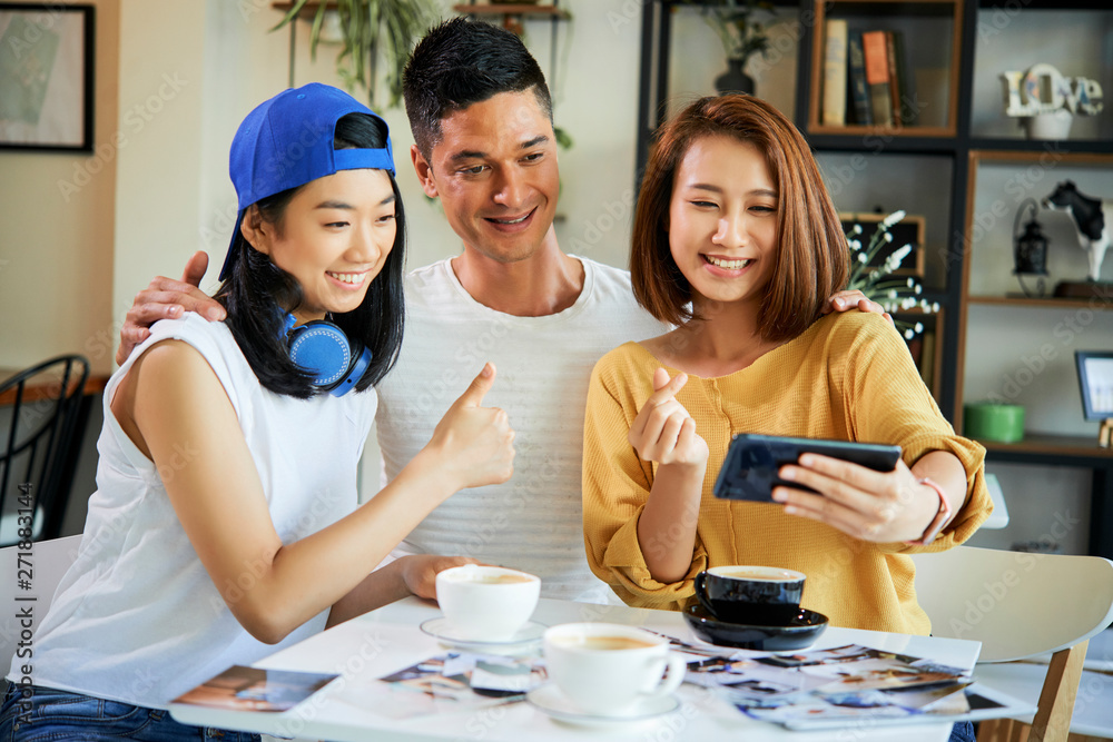 Group of hugging friends sitting at cafe table and smiling and posing for selfie Group of hugging friends sitting at cafe table and smiling and posing for selfie