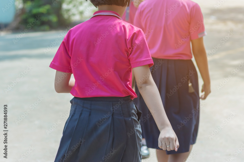Back view of happiness primary girl students in pink shirt and blue skirt walk to classrooms with their friends. Back view of happiness primary girl students in pink shirt and blue skirt walk to classrooms with their friends.