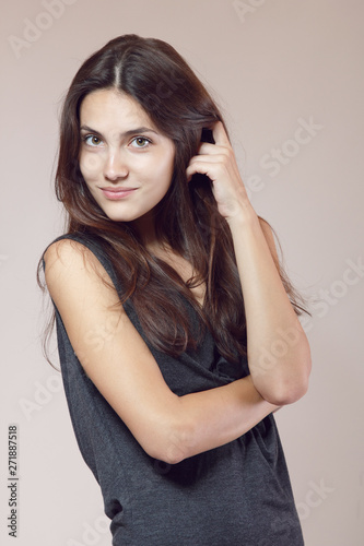 Fashion model. Young woman posing in studio. Beautiful caucasian smiling girl over gray background, image toned.
