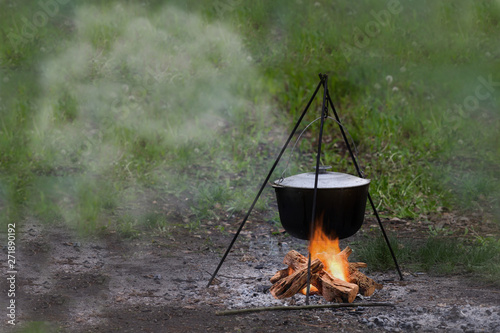 Outdoor country side cuisine with cauldron metal pot kettle for cooking outdoor in the middle of the nature near the camp with the campfire, cooking at the camp fire traditional dish. Space for text