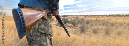 Obraz na plátně Silhouette of a hunter with a gun in the reeds against the sun, an ambush for du